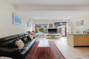 a living room with a black leather couch at Black Dolphin Waterfront Apartment in San Remo