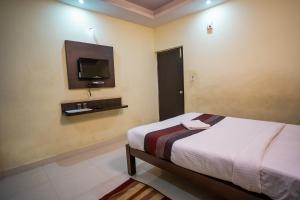 a bedroom with a bed and a tv on the wall at HOTEL PRAKAASH COMFORTS in Vānivilāsa Puram