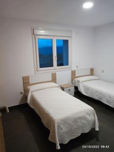 duas camas num quarto com duas janelas em Casa con vistas a la Sierra de Guadarrama em Guadarrama