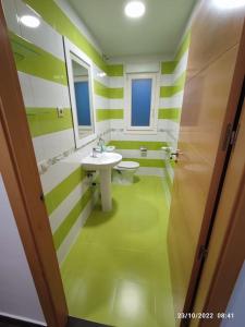 zieloną i białą łazienkę z umywalką i toaletą. w obiekcie Casa con vistas a la Sierra de Guadarrama w mieście Guadarrama