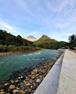 a river with rocks and mountains in the background at Rainbow Lodge Tambatuon in Kota Belud