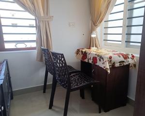 mesa y silla en una habitación con mesa y ventana en PRAKRITI HOMESTAY Fortkochi Air Conditioned Rooms, en Kochi
