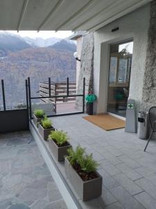 a patio with potted plants and a view of the mountains at Hotel Ristorante Miravalle in Teglio