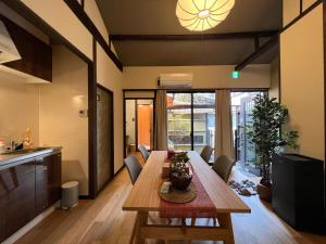 京都的住宿－至の宿-京都南 Traditional Machiya Guesthouse，厨房以及带木桌和椅子的用餐室。