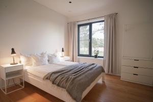 a white bedroom with a bed and a window at Maasika Villa 