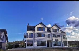 a large white house with a blue sky at Apartament Kosakowo z Tarasem II in Kosakowo