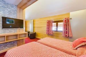 a bedroom with two beds and a flat screen tv at Le Castillan in L'Alpe-d'Huez