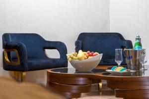 2 blaue Stühle und ein Tisch mit einer Schale Obst in der Unterkunft Al Yarmouk International Hotel in Bagdad