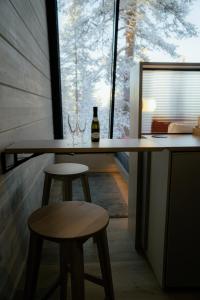 a table with two wine glasses and two stools at Salla Wilderness Lodges in Salla