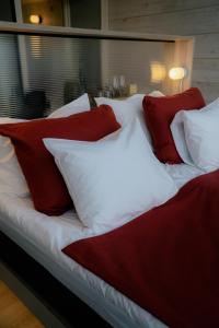 a bed with red and white pillows on it at Salla Wilderness Lodges in Salla