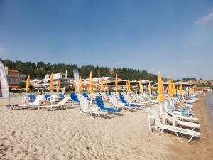 een groep stoelen en parasols op een strand bij Hotel Almira in Agia Triada