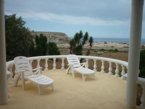 two white chairs sitting on a balcony overlooking the ocean at Oasi Di Casablanca in Lampedusa