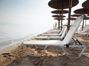 a row of lounge chairs and umbrellas on the beach at Hotel Almira in Agia Triada