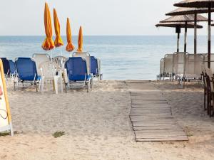 a group of chairs and umbrellas on the beach at Hotel Almira in Agia Triada