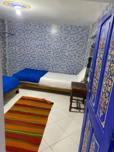 sypialnia z łóżkiem, niebieskimi drzwiami i dywanem w obiekcie Hostel Essassi 23 w Marakeszu