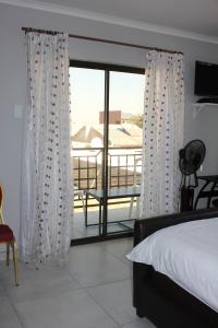 a bedroom with a bed and a view of a balcony at Coco Palm Bed & Breakfast in Windhoek