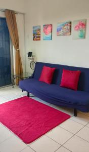 Apartment Next to Axiata Arena, Stadium Bukit Jalil في كوالالمبور: أريكة زرقاء في غرفة المعيشة مع سجادة وردية