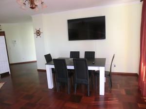 a dining room table with black chairs and a flat screen tv at Formosa Sunset in Funchal
