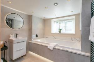 ein Badezimmer mit Badewanne, Waschbecken und Spiegel in der Unterkunft Luxurious one bedroom house in Embsay