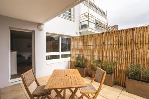 un patio con una mesa de madera, sillas y una valla en Le Jardin d'Ulysse - 2 chambres avec parking en Nantes