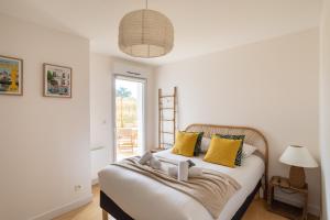 una camera da letto con un grande letto con cuscini gialli di Le Jardin d'Ulysse - 2 chambres avec parking a Nantes