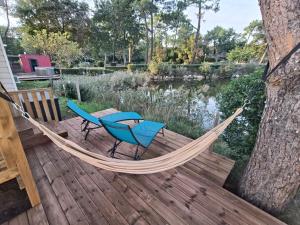 a hammock on a deck with a table and two chairs at Mobil home camping Les ViVIERS Cap Ferret in Claouey