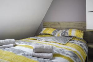 a bed with yellow and gray blankets and pillows at Apartman Maslacak in Divčibare