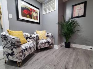 a living room with two chairs and a plant at PRIVATE & COMFORTABLE Full house near Royal Alexandra Hospital Stadium Downtown & Mall Access in Edmonton