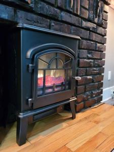a black fireplace in a room with a brick wall at PRIVATE & COMFORTABLE Full house near Royal Alexandra Hospital Stadium Downtown & Mall Access in Edmonton
