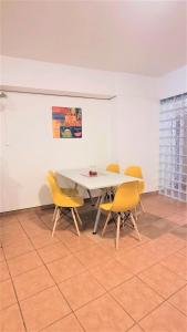 a dining room with a white table and yellow chairs at Driopon Apartment in Athens