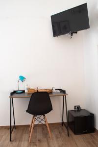 a desk with a chair and a television on a wall at Maison L'amuri in Palermo