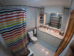 a bathroom with a colorful shower curtain and a toilet at Comparte Espacio en Chiclana in Chiclana de la Frontera