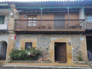 a stone house with a balcony and a wooden door at Casas las Carolinas in Anaz