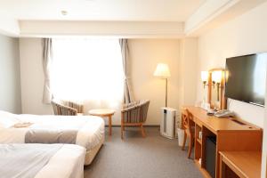 a hotel room with two beds and a flat screen tv at Imabari Urban Hotel (New Building) in Imabari