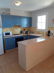 La cuisine est équipée de placards bleus et d'un réfrigérateur blanc. dans l'établissement Vacances Vaison la Romaine, à Vaison-la-Romaine