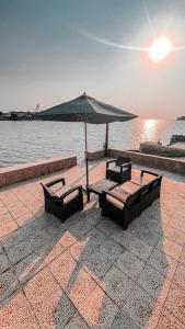 einen Tisch und Stühle mit Sonnenschirm und Wasser in der Unterkunft درة العروس فيلا البيلسان الشاطي الازرق in Durrat Al-Arus