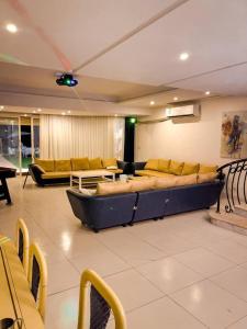 ein großes Wohnzimmer mit einem großen Sofa und Tischen in der Unterkunft درة العروس فيلا البيلسان الشاطي الازرق in Durrat Al-Arus
