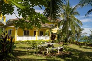 a yellow house with a picnic table in the yard at Villa Camotes in Camotes Islands
