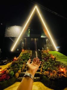 a person raising their hand in front of a garden at The Edgware Cabana in Nuwara Eliya