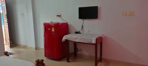 トリバンドラムにあるAnamika Holiday homeの小さなテーブルと赤い冷蔵庫が備わる客室です。