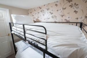um quarto com um beliche de metal com lençóis brancos em Quiet 2 Bedroomed Cottage, near the Lakes em Carnforth