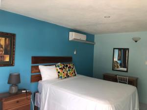 um quarto com uma cama e uma parede azul em Airport Beach Hotel em Montego Bay