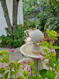 a bird bath in a garden with pink flowers at Casa di Sofia in Castellana Grotte