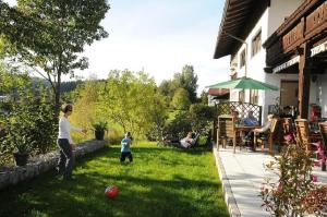 una mujer y un niño jugando con una pelota en un patio en Pension Waldeck, en Langdorf