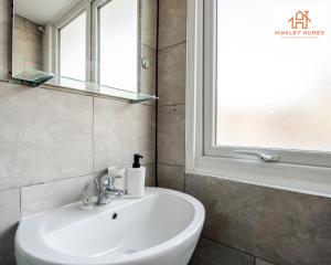 a bathroom with a white sink and a window at Large & Spacious 3 Bedroom House with Parking & Wifi By Hinkley Homes Short Lets & Serviced Accommodation in Liverpool