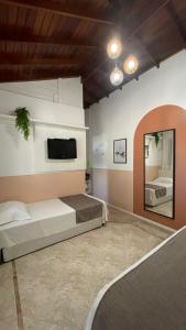 Pousada Casa Mariscal في بومبينهاس: غرفة نوم بسريرين وتلفزيون على الحائط