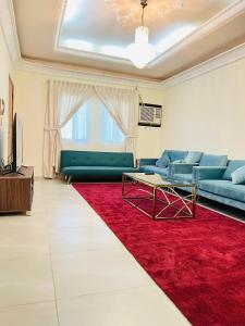 un soggiorno con divano e tappeto rosso di FANATEER SUDAYER VILLA a Al Fanātīr