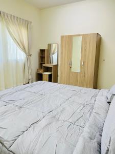 Un dormitorio con una gran cama blanca y una ventana en FANATEER SUDAYER VILLA, en Al Fanātīr