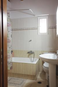 y baño con bañera, aseo y lavamanos. en ΚΑΛΟΣΚΟΠΗ Luxury House, en Kaloskopí