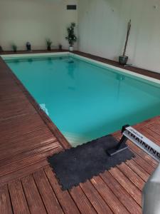 a large swimming pool with a wooden deck at La Picardière in Perdreauville